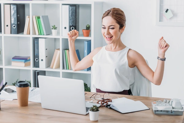 woman with a laptop celebrating