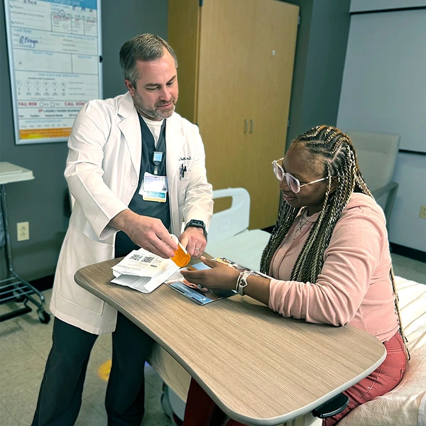 Jacob Wetsell, PharmD, BCPS reviews medication with a patient.