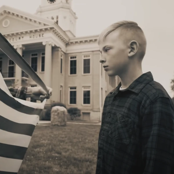 Why I Stand music video still of boy with flag